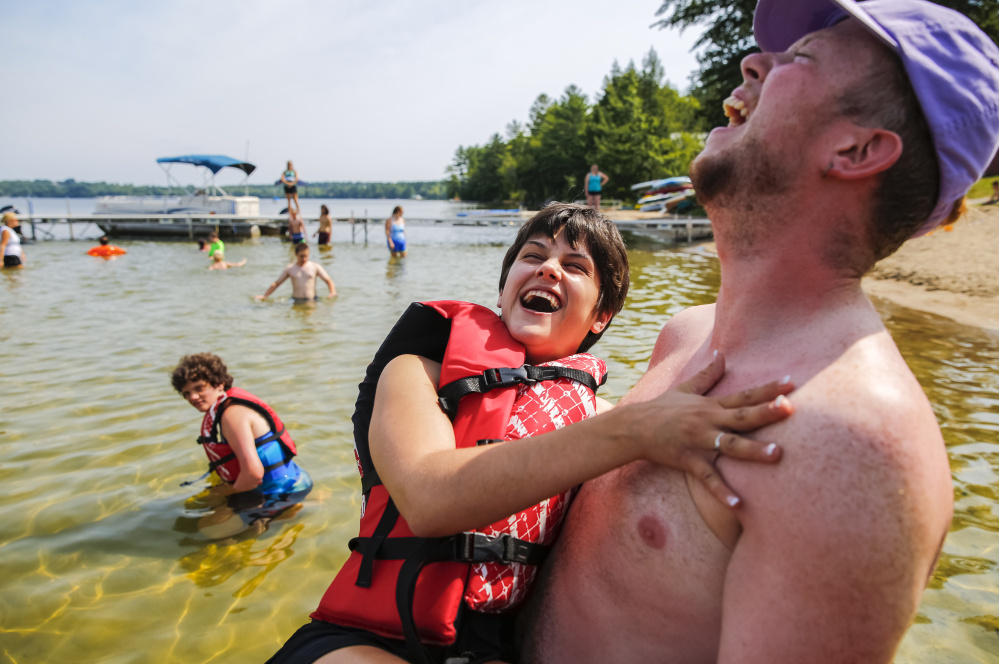 Pine Tree Camp counselor Andrew Sinclair carries camper Kelley Handy out for a swim in North Pond last August in the Kennebec County town of Rome. Maine is not a leader among states in providing outdoor recreational activities to people with physical disabilities.